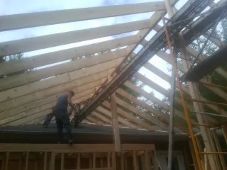 Rafters going up over a new addition with a worker on the wall in Egypt