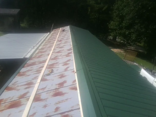 Old rusted panels beside newly installed green metal roofing — Wind Damage Roof Repair by Roofing Brothers in Egypt