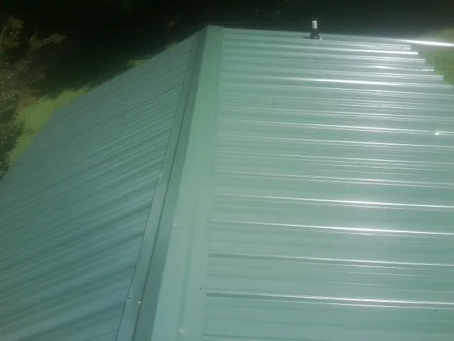 New green metal panels meeting at the ridge of a roof — Flat Roof Repair work by our crew in Egypt