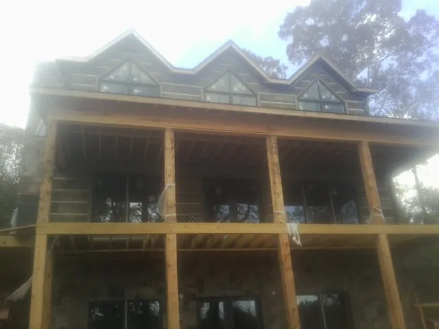 Dormers and porch framing on a large log home under construction — Roof Coating work by our crew in Egypt