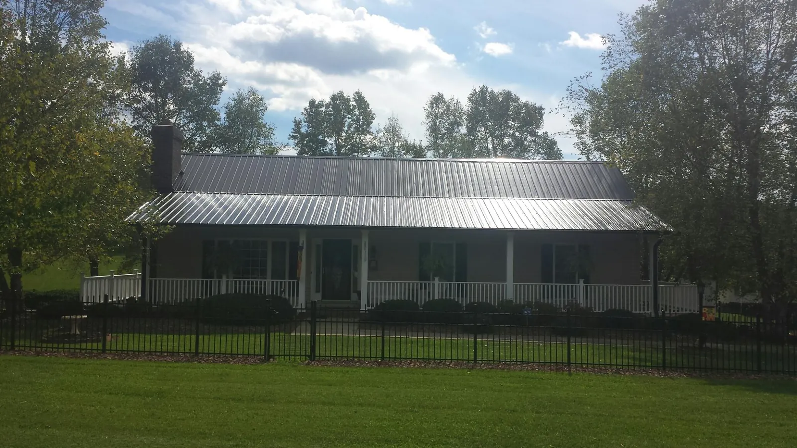 Gray metal roof on a brick ranch with a full width front porch — Gutter Guard Installation work by our crew in Egypt