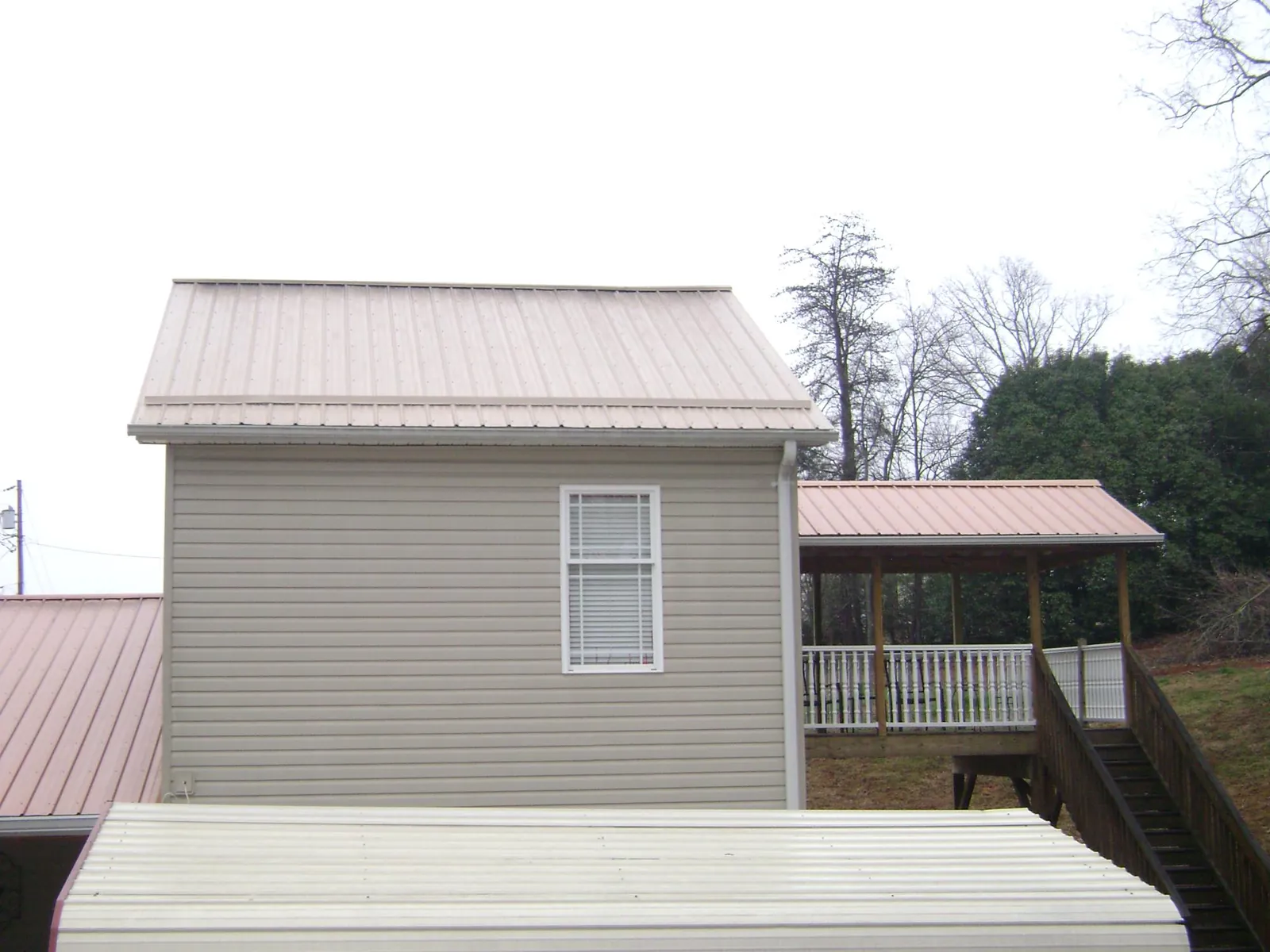 Tan metal roofs on a two story addition and attached porch, from a Roof Replacement job in Egypt
